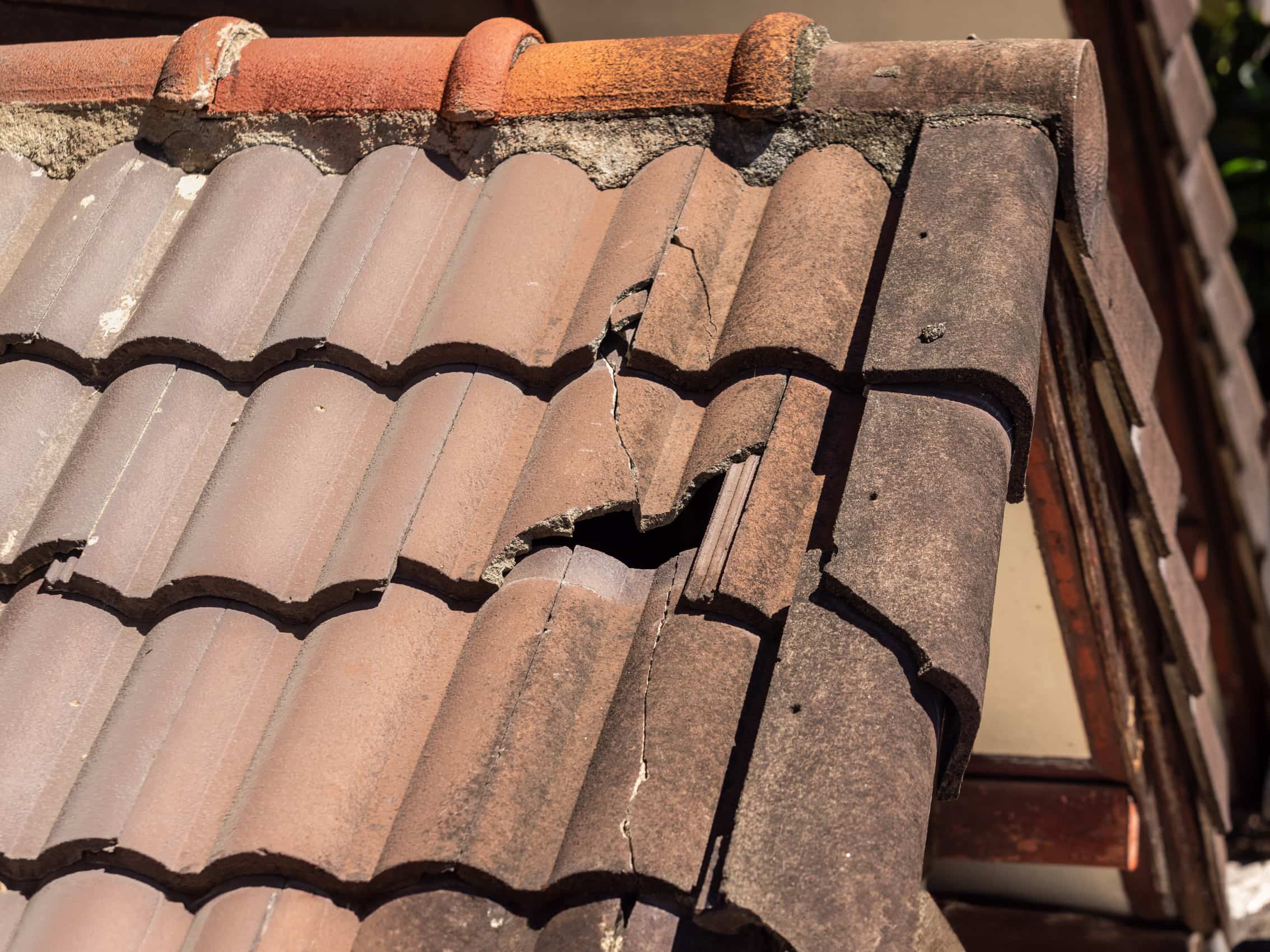 Cracked and broken concrete tile requiring urgent roof repairs
